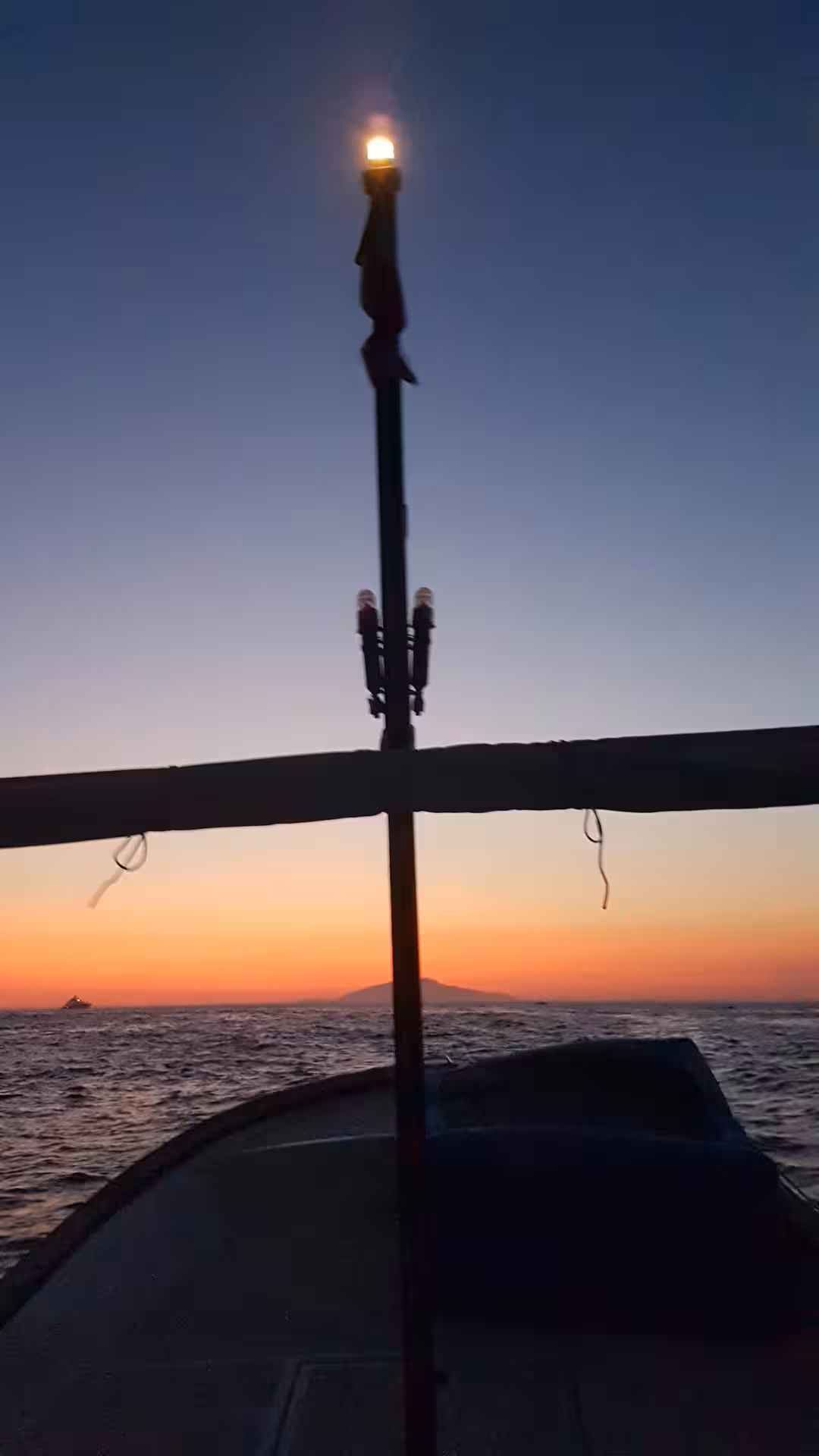 Sunset boat deck view with glowing lamp over calm sea, part of From Dusk Till Night immersive night tour