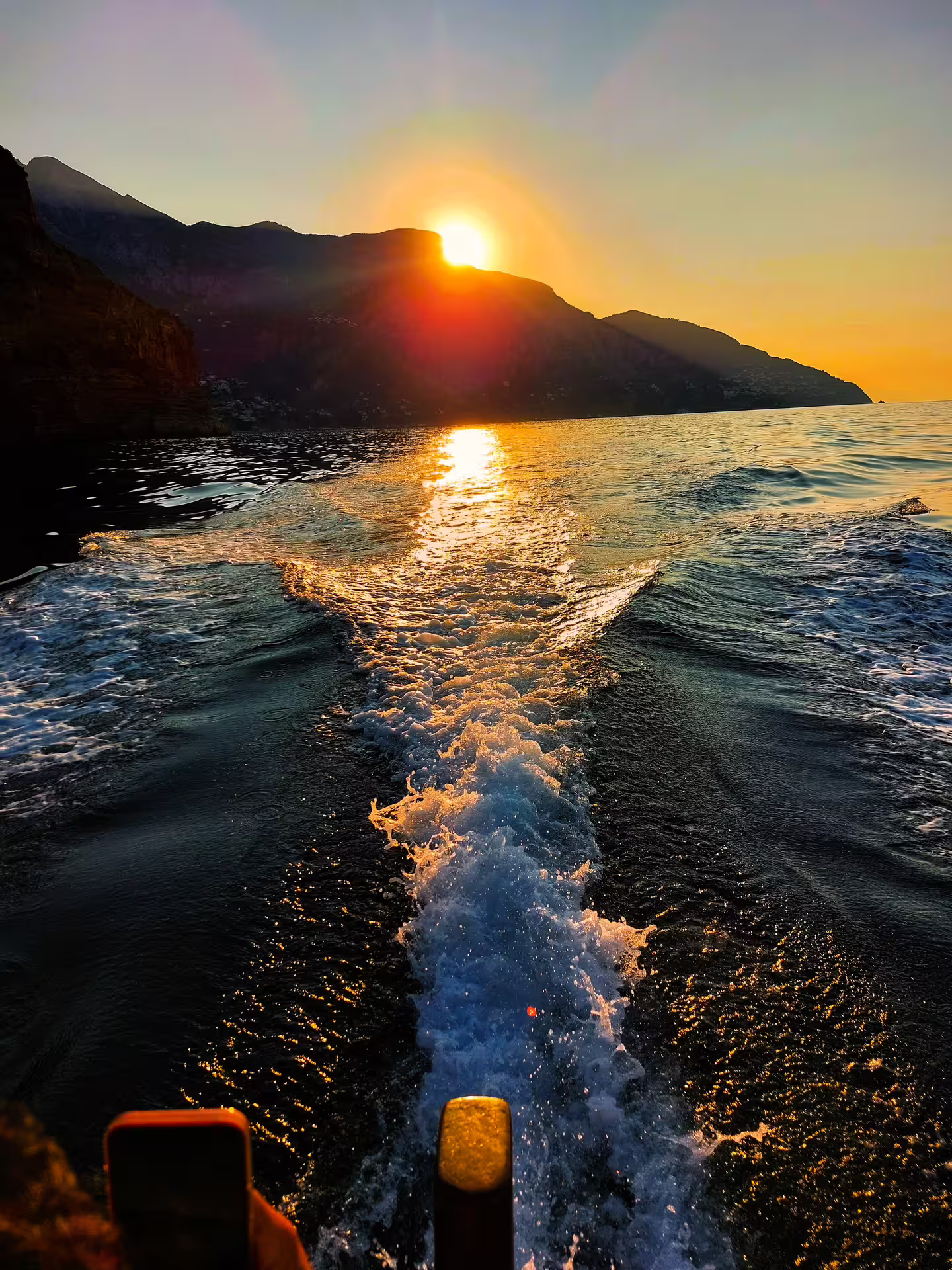 Golden sunset boat ride with sea wake and coastal cliffs, From Dusk Till Night immersive experience