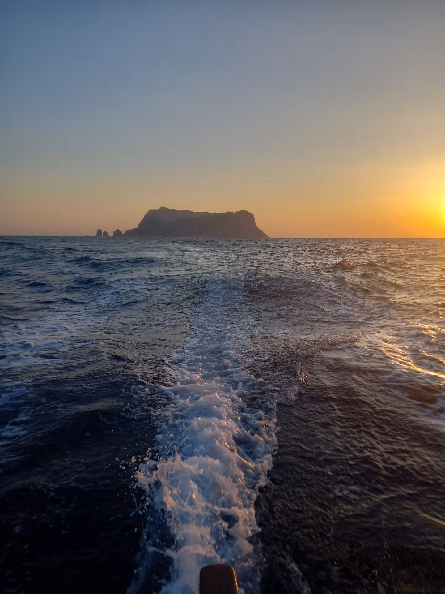 Golden-hour boat wake on the ocean with distant cliffs, From Dusk Till Night immersive evening sea experience tour