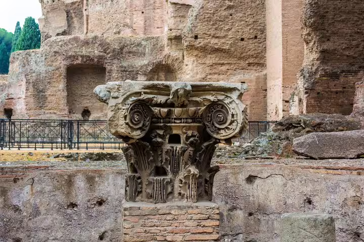 Ornate carved Roman column capital displayed amid the monumental ruins of the Baths of Caracalla on a VIP guided visit