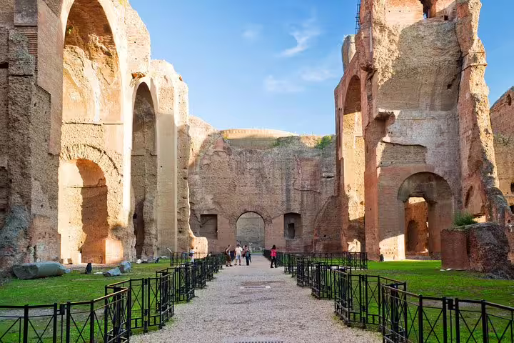 Visitors walking between towering arches inside the Baths of Caracalla on an exclusive Rome private guided tour with VIP entry