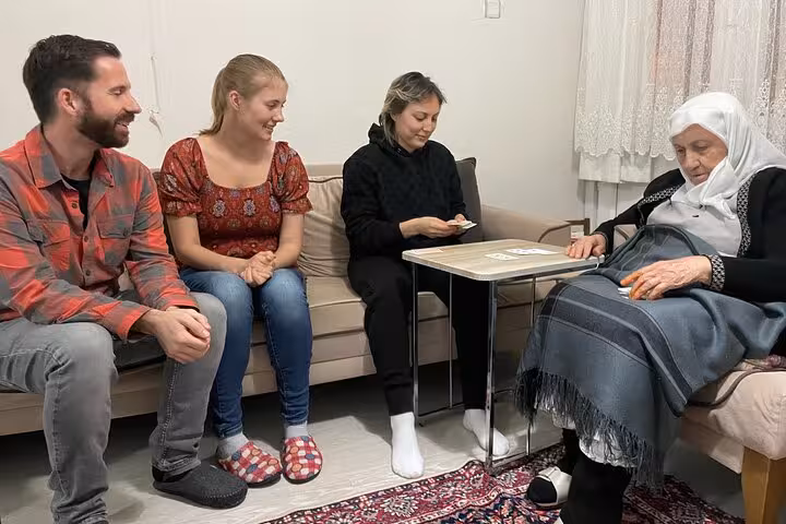 Small group shares card game and Turkish tea with local grandma in a cozy home, cultural Istanbul experience