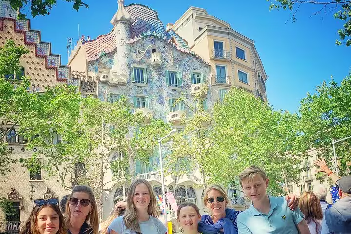 Tourists admire the colorful Gaudi architecture of Casa Batlló on a sunny day in Barcelona's Gothic Quarter.