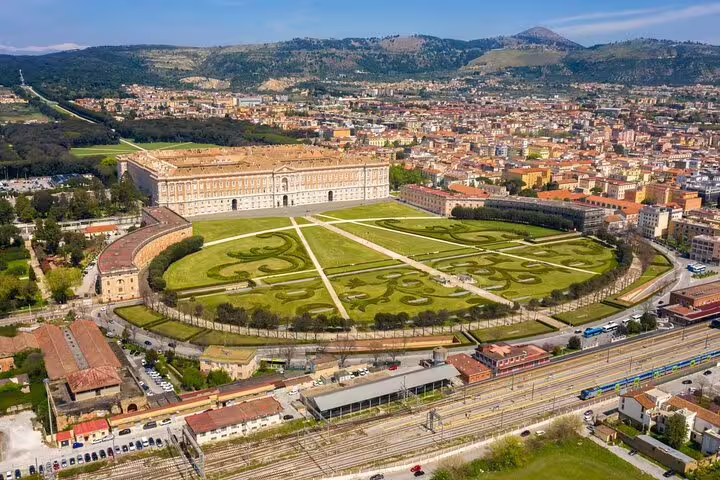 Panoramic drone view of Caserta Royal Palace, vast landscaped gardens and cityscape, included in private shuttle tour