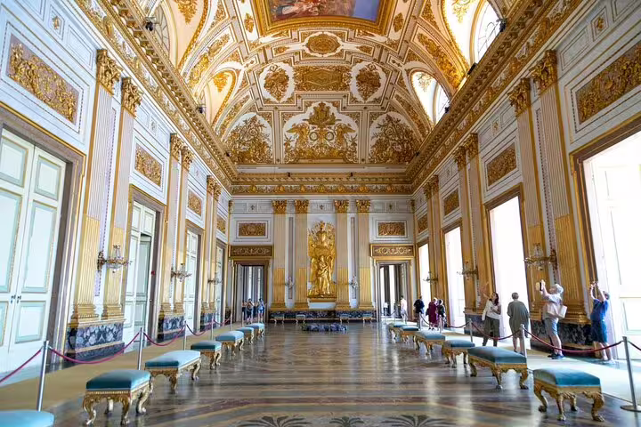 Tourists explore the opulent gold-trimmed throne room of Caserta Royal Palace on a private guided palace and gardens tour
