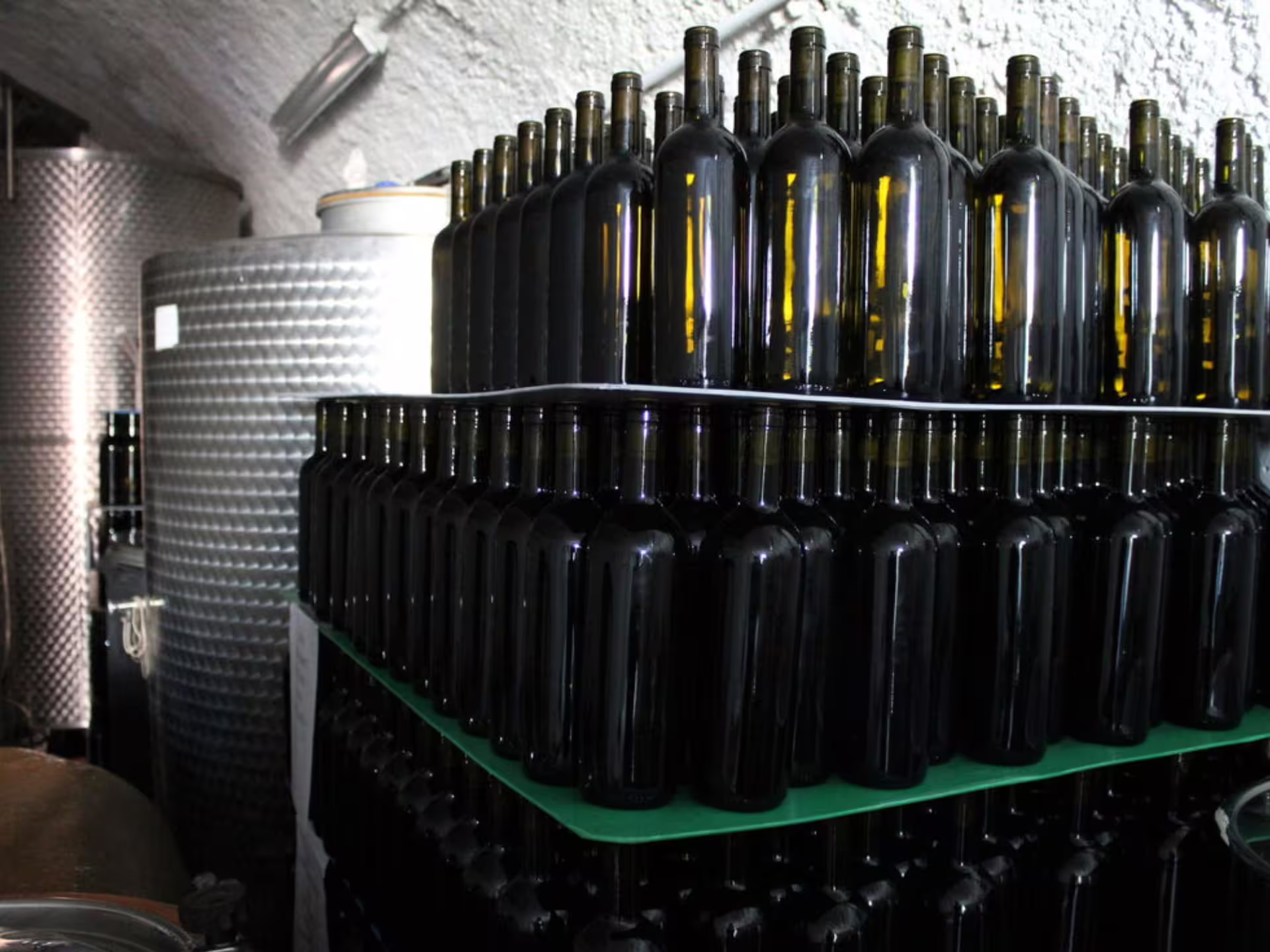 Stacks of wine bottles in a rustic cellar, ready for tasting during the Castelli Romani tour experience.