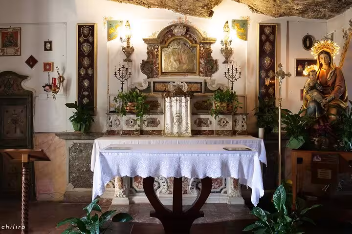 Charming interior of a rustic chapel in Castelmola, featuring ornate altar and religious iconography.