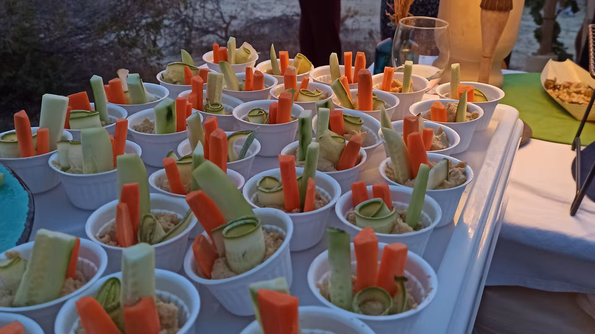 Appetizing vegetable cups with dips displayed at a sunset wine tasting event in Castelsardo vineyard.