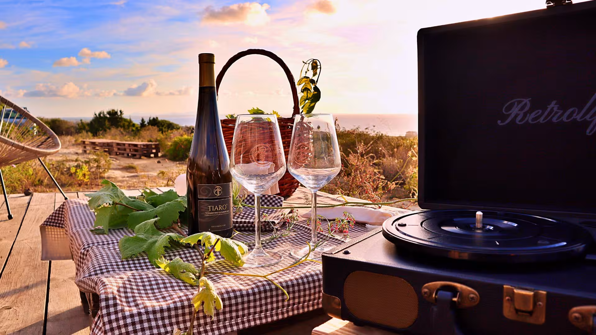 Wine glasses and a bottle set on a table with a coastal view, perfect for sunset wine tasting in Castelsardo.