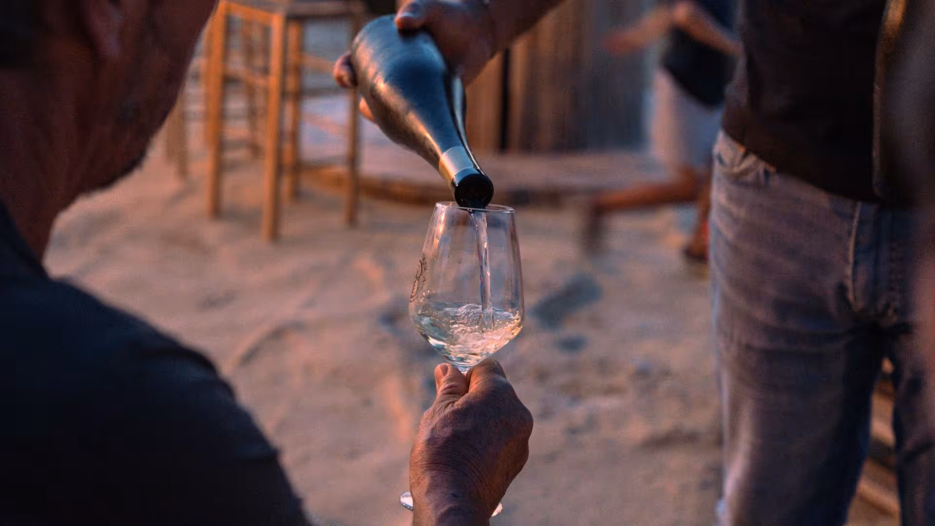 Close-up of wine being poured into a glass at sunset, enhancing the Castelsardo vineyard wine tasting event ambiance.