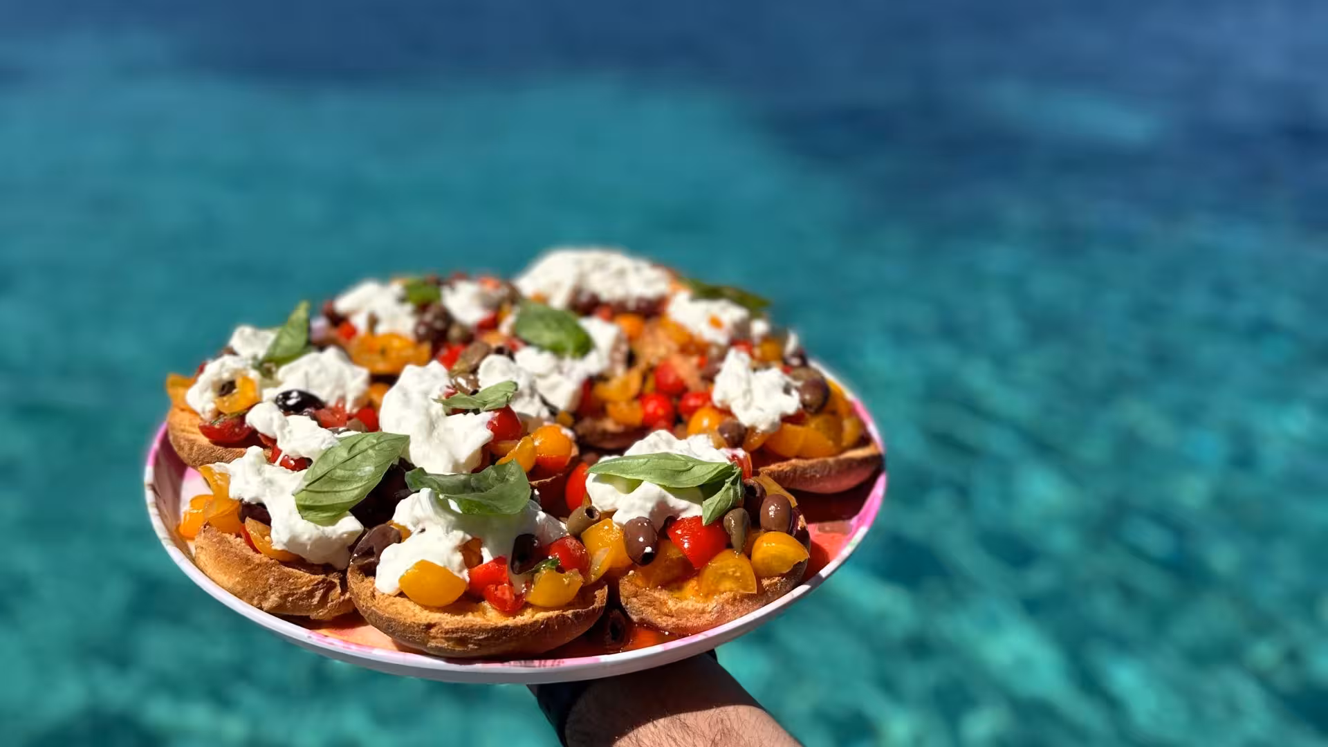 Delicious Mediterranean bruschetta served on a catamaran in the Gulf of Asinara, with crystal-clear turquoise waters.