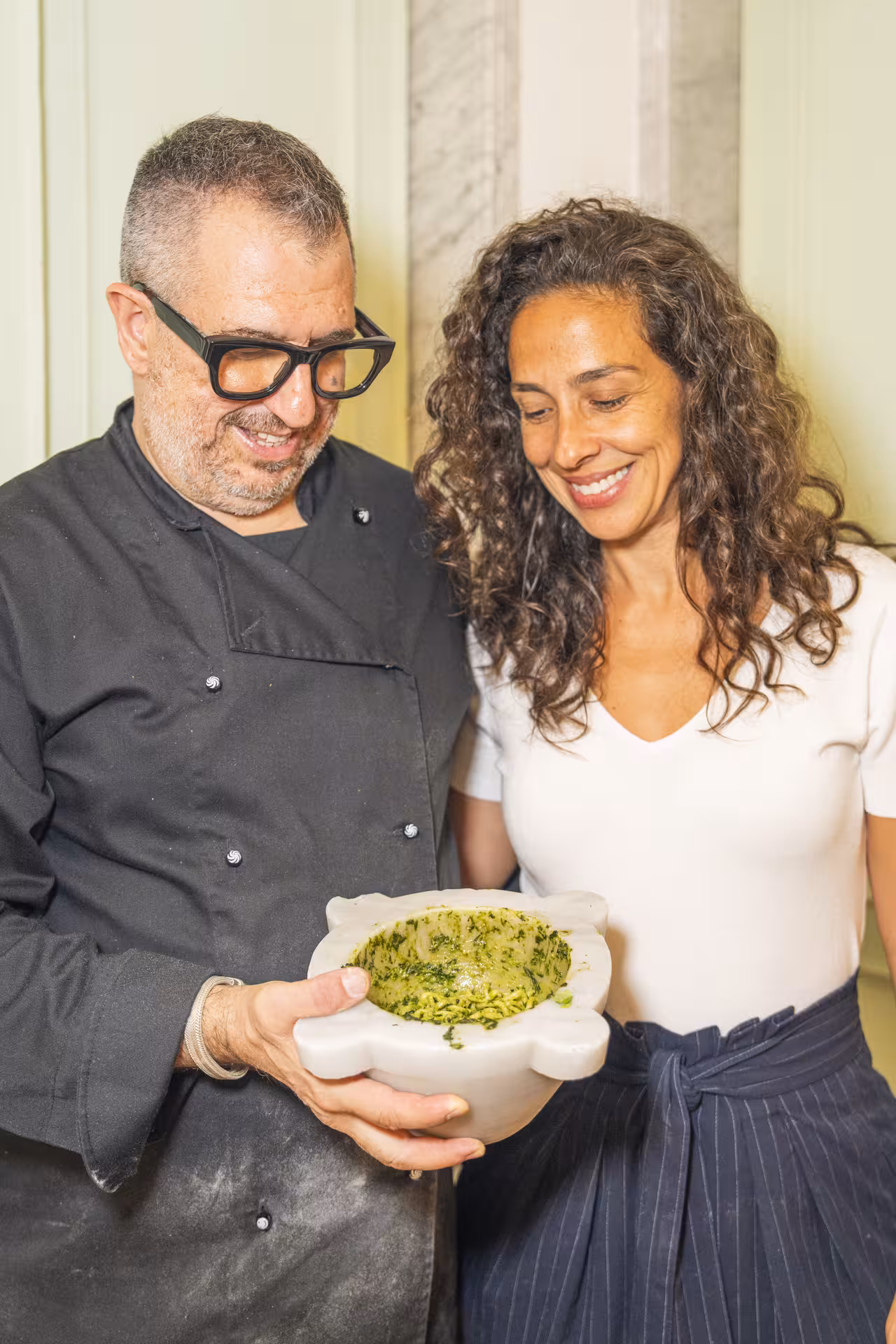 Chef and guest smile while holding freshly made pesto in a traditional mortar during the tour.