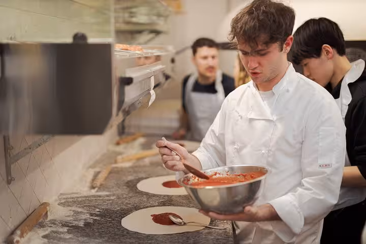 Chef preparing fresh tomato sauce during a pizza cooking class near Piazza Navona, Rome.