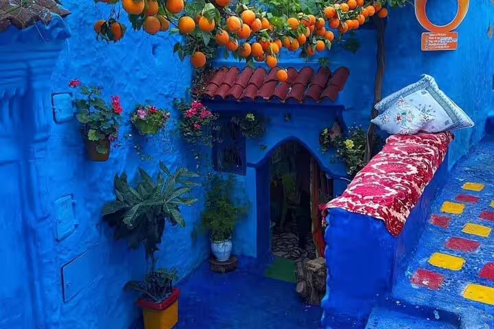 Vibrant blue courtyard with orange trees and painted stairs in Chefchaouen, 2 days tour from Casablanca