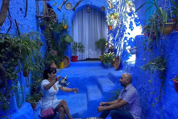 Couple enjoying Moroccan mint tea in a blue Chefchaouen courtyard during a 2-day Chefchaouen trip from Casablanca
