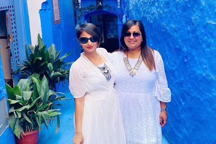 Two travelers in white dresses in Chefchaouen blue medina doorway, 2-day Casablanca to Blue City tour