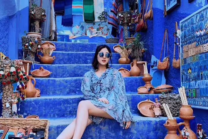 Traveler on Chefchaouen blue steps with Moroccan pottery, highlight of 9-day Tangier to Marrakech tour