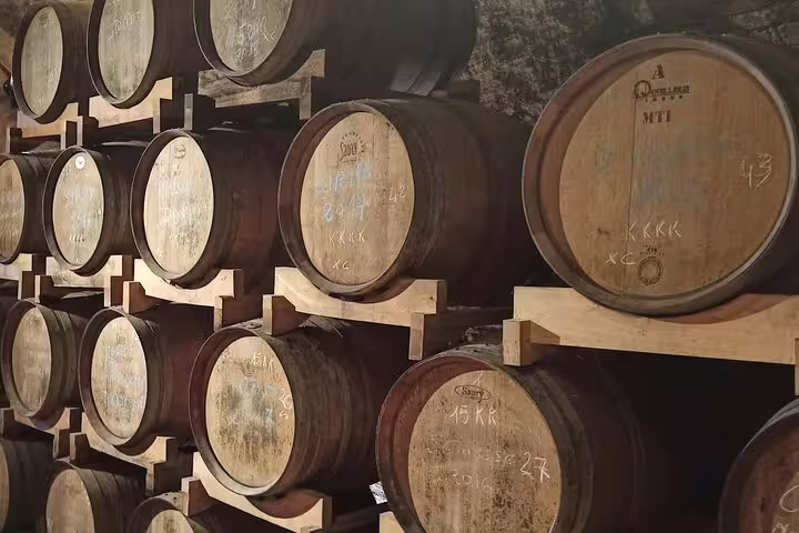 Oak wine barrels aging Chianti Classico in a traditional Tuscan cellar on a half-day San Gimignano wine tour