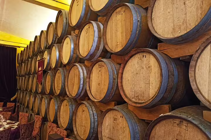 Stacked oak barrels in an atmospheric Chianti wine cellar visited on a private afternoon tour of two Tuscan estates