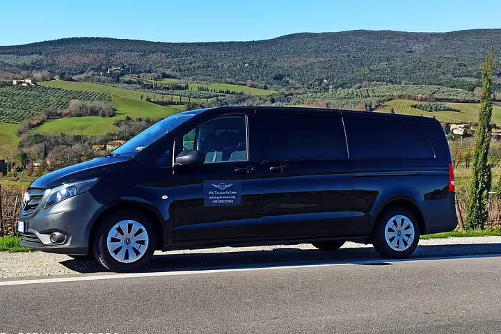 Comfortable black minivan for Chianti Classico half-day wine tour driving through rolling Tuscan hills and vineyards