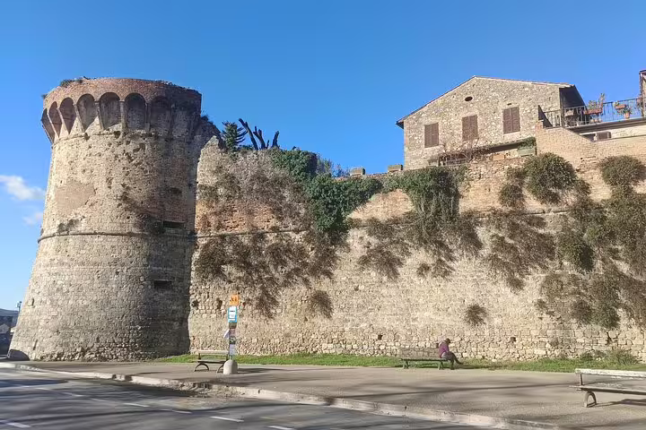 Ancient stone fortress walls and medieval tower of San Gimignano seen during a Chianti half-day wine tour in Tuscany, Italy