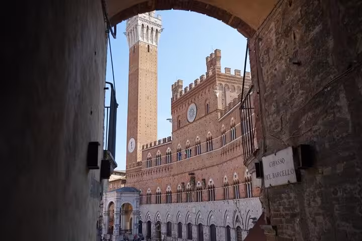 Discover the historical charm of Siena's iconic Torre del Mangia through an ancient archway on your Chianti tour.
