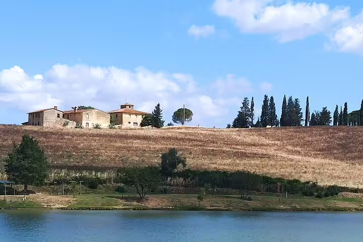 Rustic Chianti farmhouse and cypress trees above a tranquil lake seen during a private afternoon wine tour in Tuscany