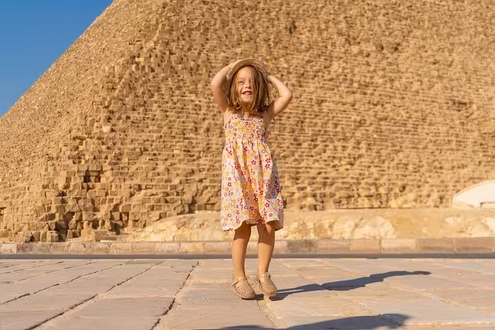 Child posing by the Great Pyramid of Giza on a family-friendly Hurghada to Cairo pyramids and museum trip