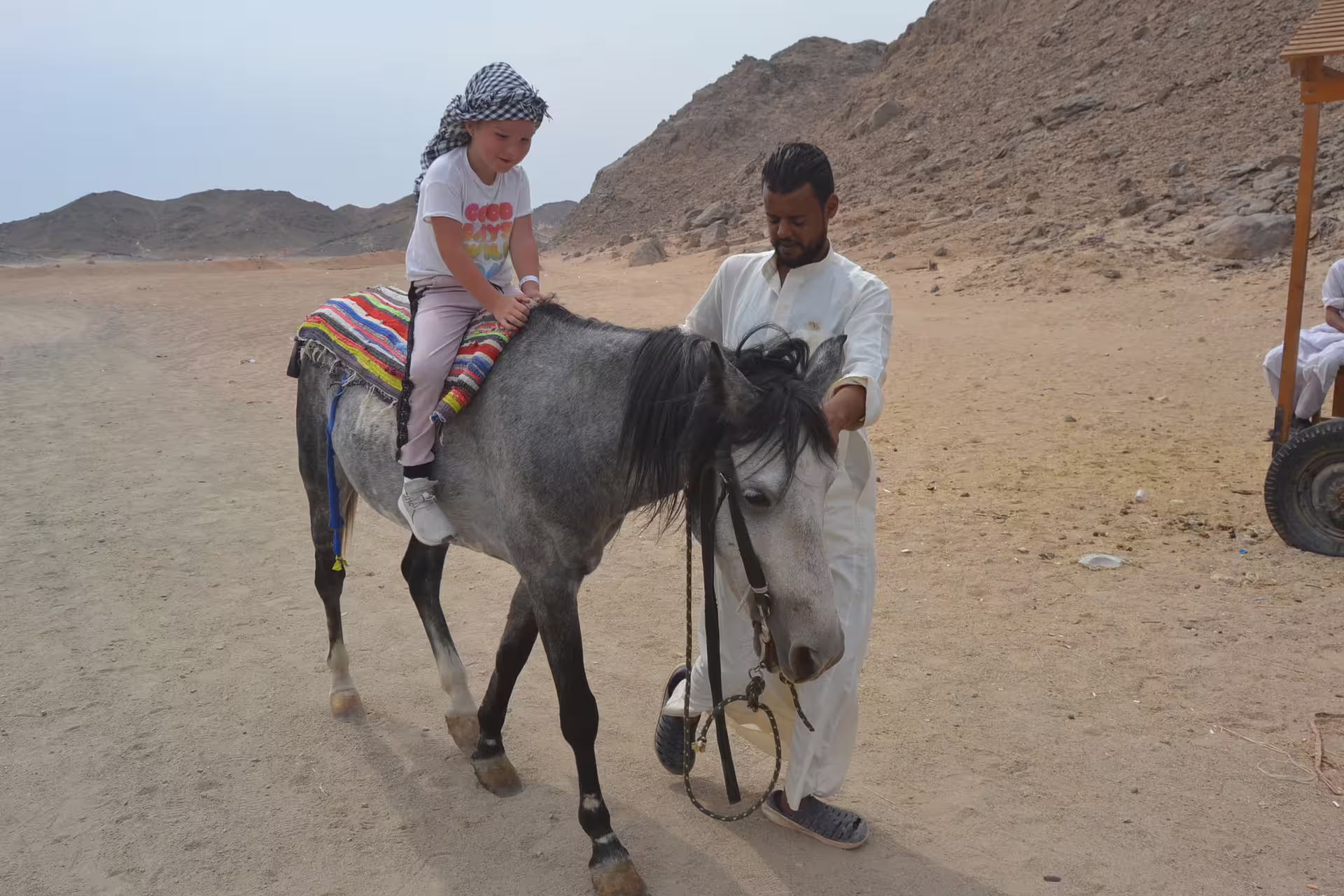 Child riding a horse with Bedouin guide in the Hurghada desert, part of a quad safari tour experience