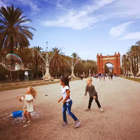 Children playing with bubbles at Arc de Triomf, Barcelona, during a family-friendly tour with churros and hot chocolate.