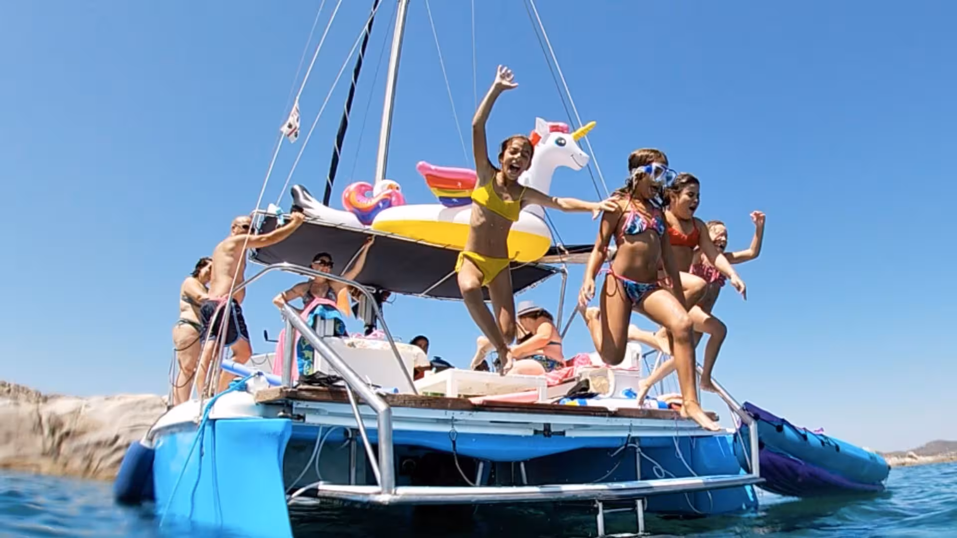 Children jumping off a catamaran into the Gulf of Asinara, enjoying a fun-filled tour from Stintino.