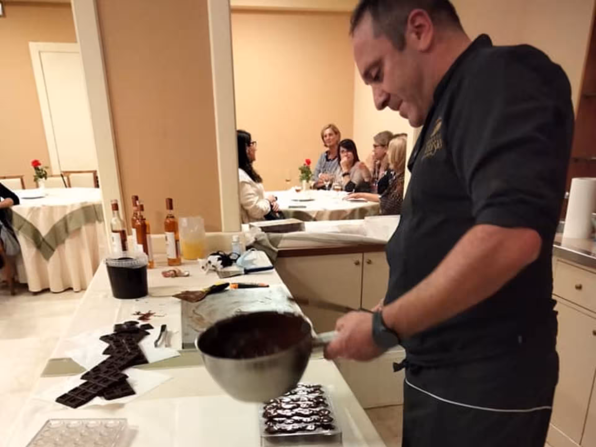 Chocolate artisan pouring melted chocolate into molds during a workshop at a Perugia chocolate factory tour.