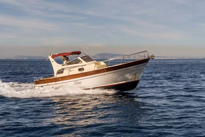 Classic Gozzo 850 cruising through the blue waters near Positano on a sunny day.