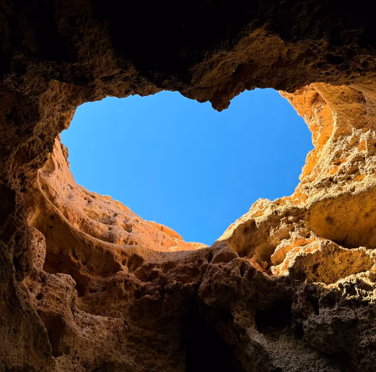 View of blue sky through a rugged rock opening on an adventurous coastal cave exploration tour.