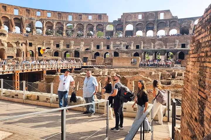 Tourists exploring the interior of the Colosseum with views of ancient architecture and historic arches.