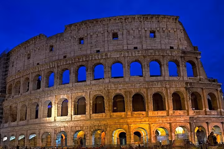 Illuminated Colosseum at night with vibrant blue sky, perfect for an evening Ancient Rome tour.