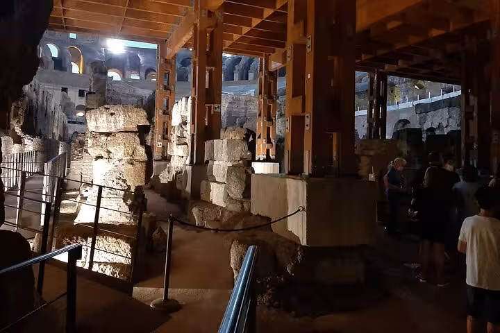 Experience the majestic interior of the Colosseum under atmospheric lighting on a Rome night tour.