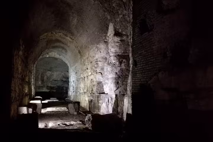 Discover the ancient stone corridors of the Colosseum's underground, lit dramatically during the night tour.