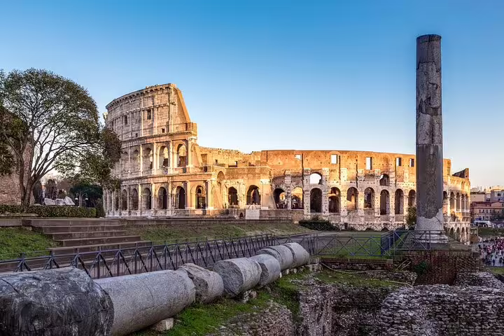 Panoramic view of the Colosseum and Roman Forum ruins in Rome at sunset, featured on a small-group guided tour