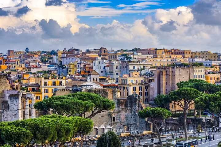 Scenic view of Rome's historic skyline with ancient ruins and lush greenery under a cloudy sky.