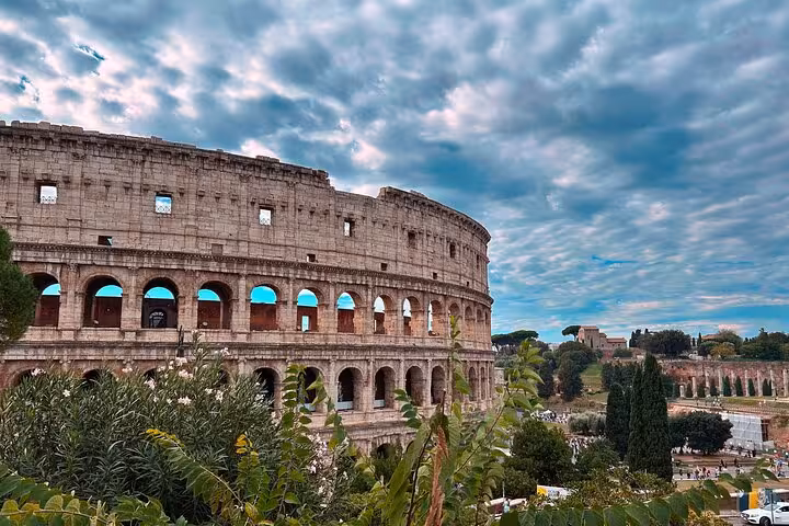 Majestic view of the Colosseum in Rome under a cloudy sky, a highlight of the Rome tour with cooking class.