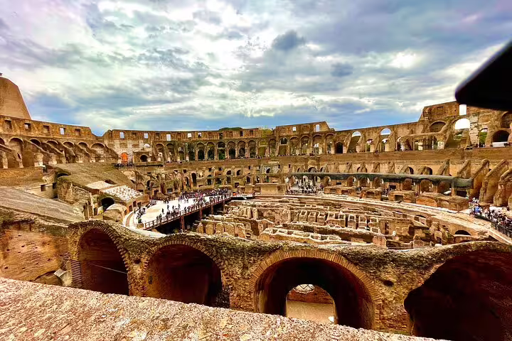 Panoramic interior view of the Colosseum in Rome on a VIP small-group tour, showing ancient arena ruins and crowds exploring