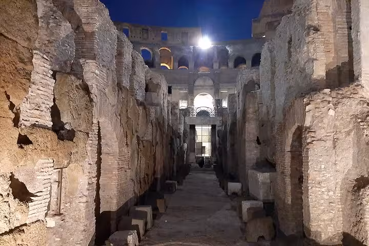 Experience the historic grandeur of the Colosseum's interior under soft night lighting on a guided tour in Rome.