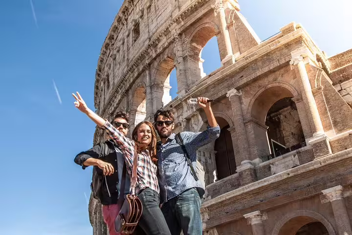 Happy friends posing in front of the Colosseum in Rome during a skip-the-line private guided tour of the arena and Forum