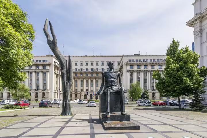 Bronze statue in Revolution Square with communist-era government building in Bucharest background