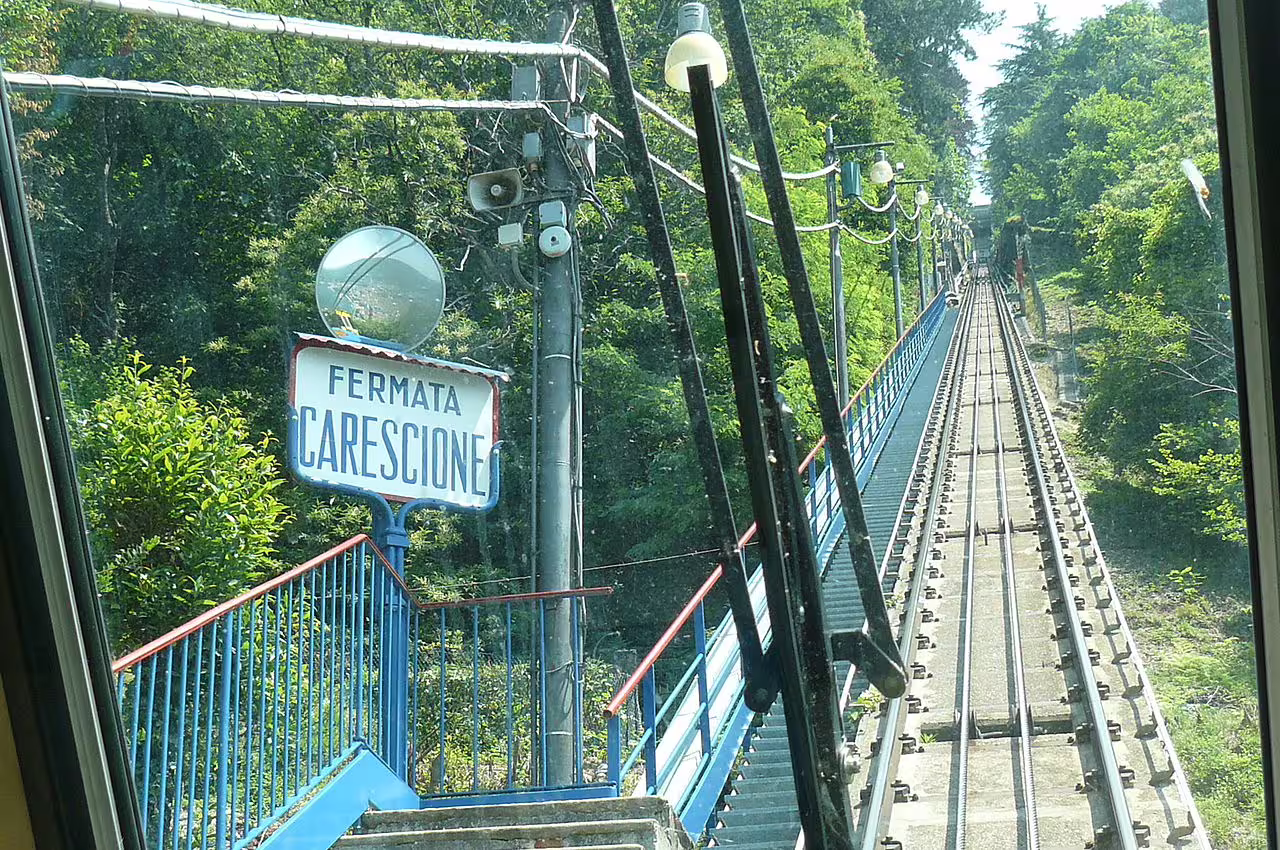 View from the Como–Brunate funicular at Carescione stop, climbing steep forested hillside above Lake Como for panoramic vistas