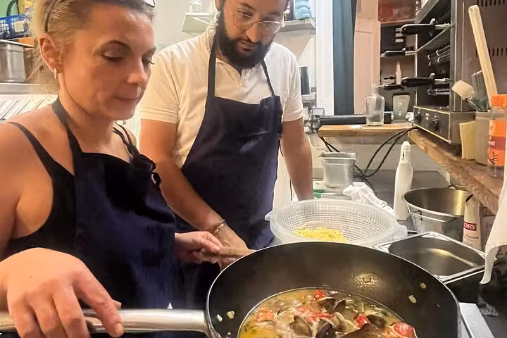 Guests cooking seafood pasta with a local chef in a Marseille kitchen, hands-on Provençal cooking workshop