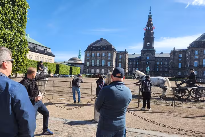 Tourists capturing the horse-drawn carriage near Christiansborg Palace during Copenhagen highlights tour.