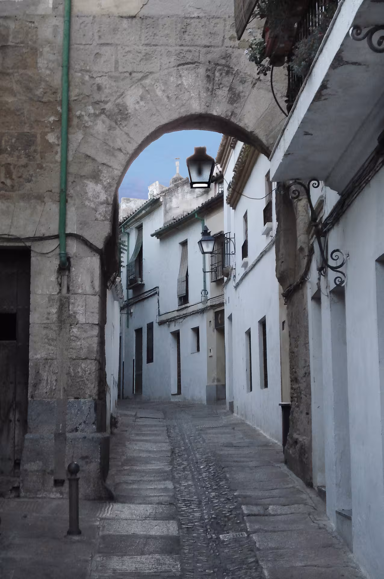 Callejón con arco de piedra y faroles en Córdoba, escenario del Free Tour Misterios y Leyendas nocturno