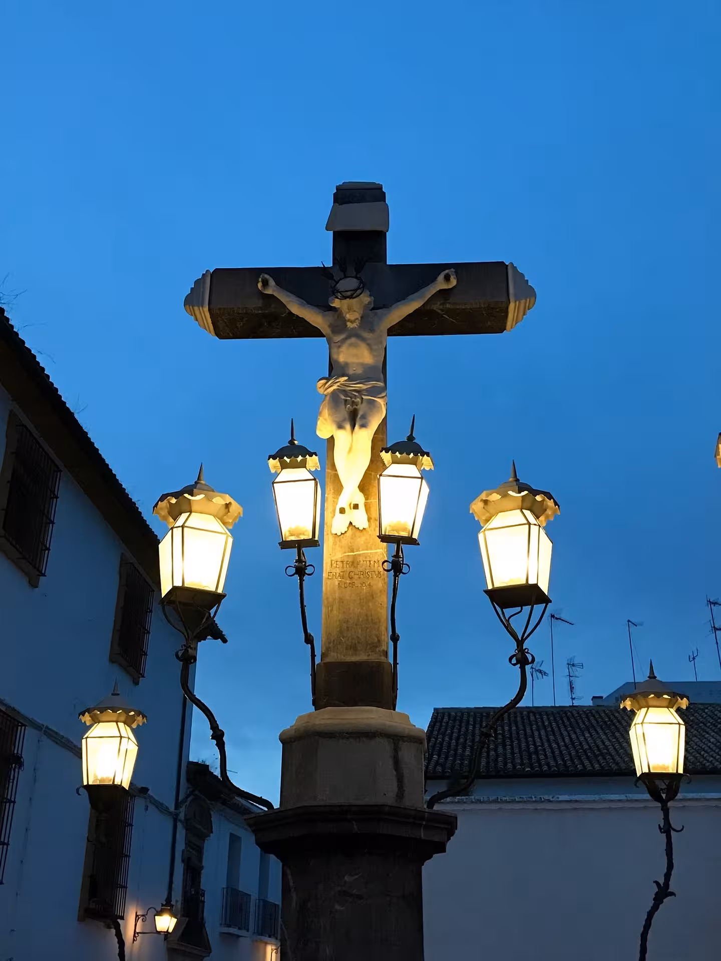 Illuminated stone crucifix and lanterns in Córdoba at dusk on Free Tour Secretos de la Axerquía